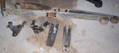 1990 Ford Bronco - Various used and rusted vehicle suspension parts are displayed on a concrete surface.