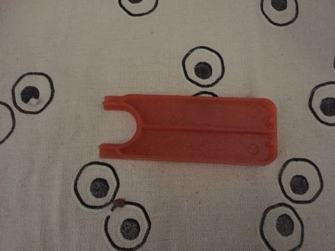 1986 Ford Bronco - An orange plastic part is shown against a patterned cloth background.