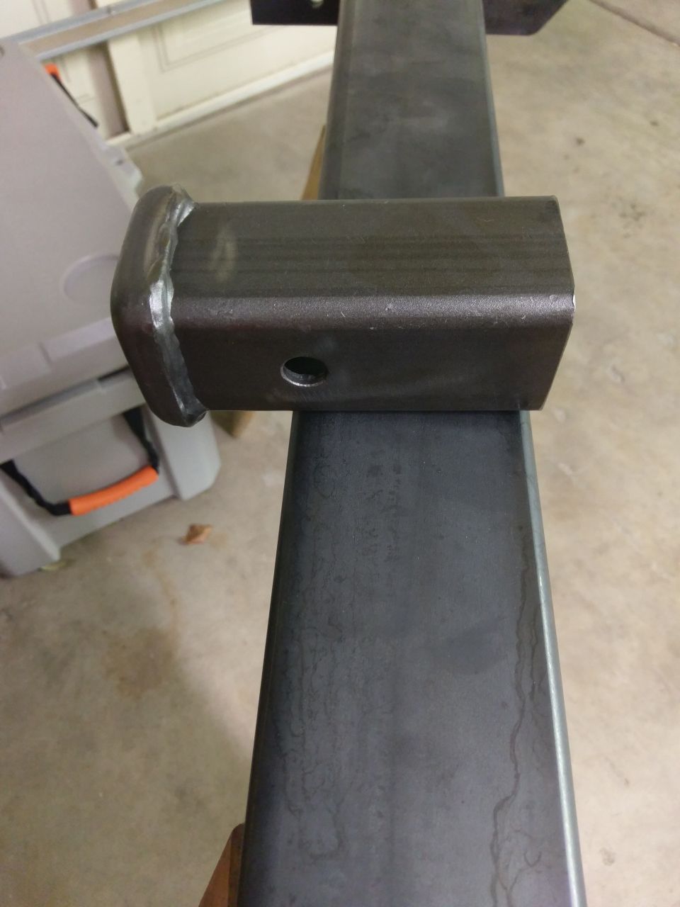 Trailer hitch receiver tube with a welded cap and a pin hole