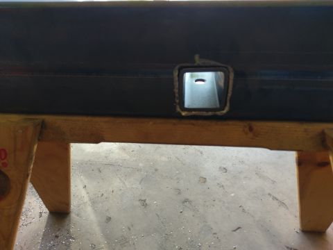 1988 Ford Bronco - A close-up view of a metal tube with a square opening, resting on wooden supports.