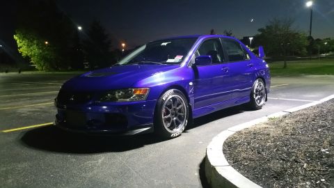 2006 Mitsubishi Evolution - A purple 2006 Mitsubishi Evolution sedan is captured from a three-quarter front view at night.