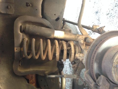 1986 Ford Bronco - Close-up view of the front suspension coil spring and brake rotor assembly on a 1986 Ford Bronco.