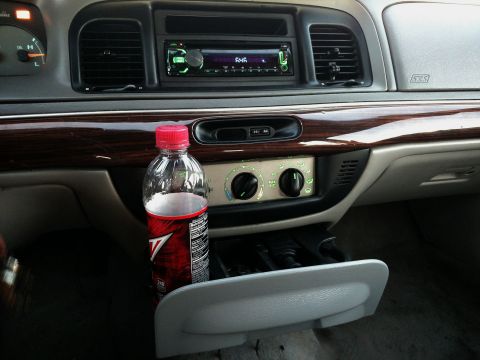 1995 Mercury Grand Marquis - The interior of a 1995 Mercury Grand Marquis shows a wood-trimmed dashboard with an aftermarket stereo and a soda bottle.