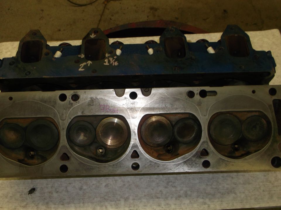 two engine cylinder heads, one blue, one silver, with valves visible