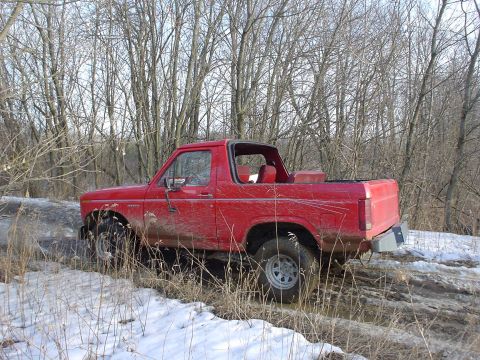 1980 Ford Bronco - This 1980 Ford Bronco is shown off-roading in a muddy and snowy environment with trees in the background.