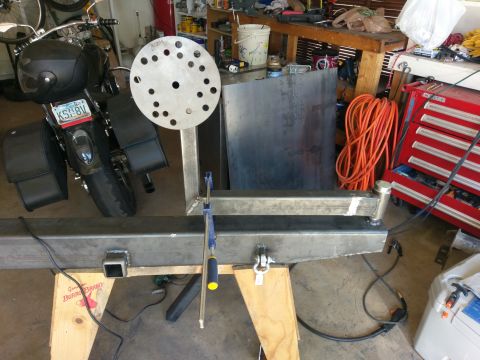 1988 Ford Bronco - A motorcycle is parked in a garage next to a metal fabrication project involving large steel beams and clamps.