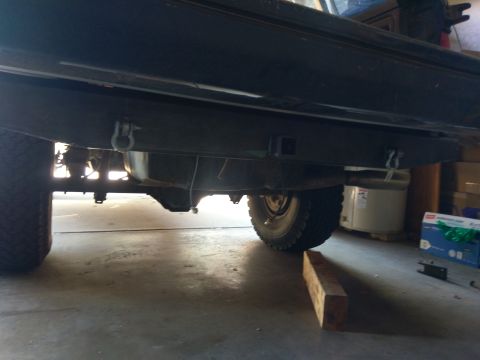 1988 Ford Bronco - Underside view of a vehicle's rear axle and tires, showing suspension components and tow hitch receiver.