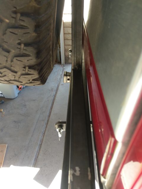 1988 Ford Bronco - Close-up view of a spare tire and the side panel of a red vehicle, with a metal frame visible.