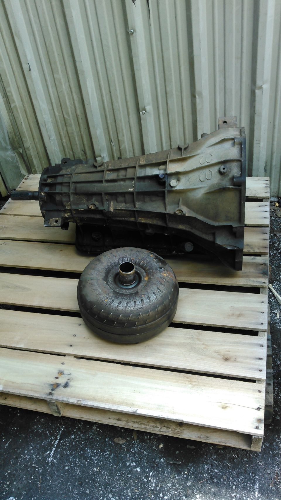 Automatic transmission and detached torque converter sitting on a wood pallet