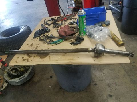 1987 Suzuki Samurai - An axle shaft and various tools are laid out on a workbench, suggesting a repair or maintenance operation.