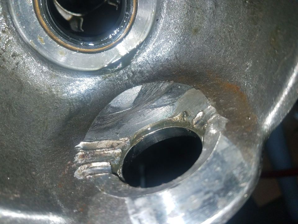 Close-up of a metal automotive part with machined openings and wear marks