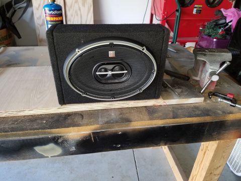 1994 Ford Bronco - A car speaker in an enclosure sits on a wooden surface, with tools and a propane torch in the background.