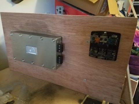1994 Ford Bronco - A car amplifier and a fuse box are mounted on a wooden panel, likely for installation.