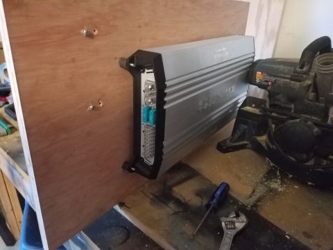 1994 Ford Bronco - A car stereo amplifier is mounted on a wooden panel, with a saw and tools visible in the background.