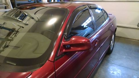 2002 Pontiac Grand Prix - Side view of a red 2002 Pontiac Grand Prix parked indoors.