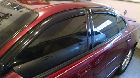 2002 Pontiac Grand Prix - Side view of a red 2002 Pontiac Grand Prix sedan, showing its vent shades and chrome accents.