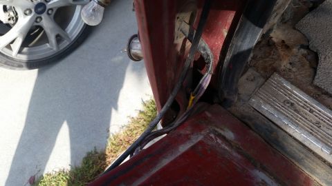 1981 Ford Bronco - Detail shot of a vehicle's interior, focusing on worn flooring, exposed wiring, and a tire visible through the open door.