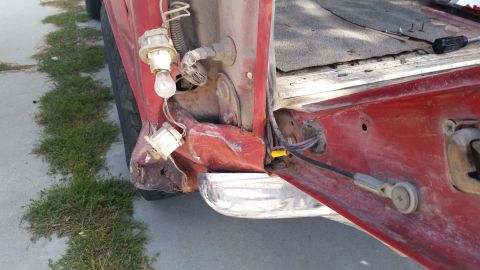 1981 Ford Bronco - Rear corner damage on a red 1981 Ford Bronco reveals exposed wiring and a broken taillight socket.
