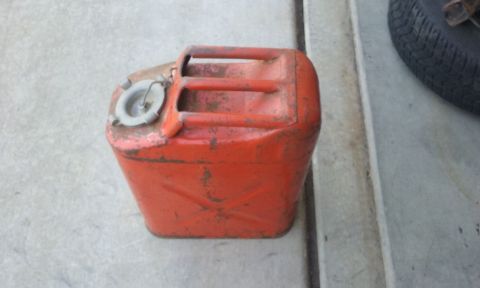 1995 Ford Bronco - This old red jerry can shows signs of rust and wear, sitting on a concrete floor.