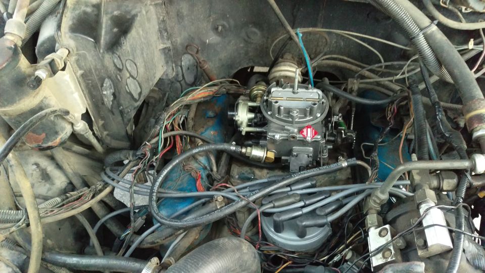Engine bay showing a carburetor, distributor, and wiring harness