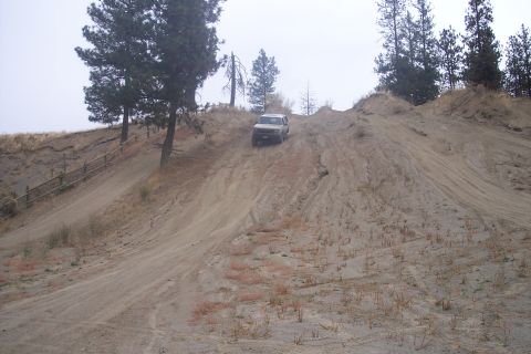1995 Ford Bronco - SUV navigates a challenging sandy hill in an off-road area.