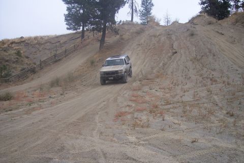 1995 Ford Bronco - An SUV navigates a steep, sandy incline on an overcast day.