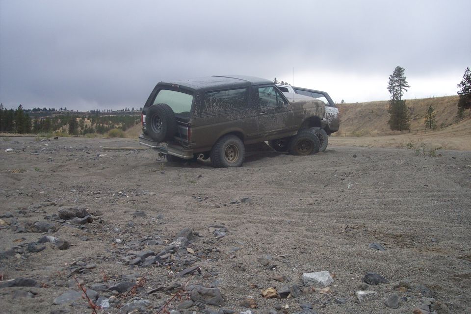 Brown Ford Bronco stuck in dirt with a spare tire on the back