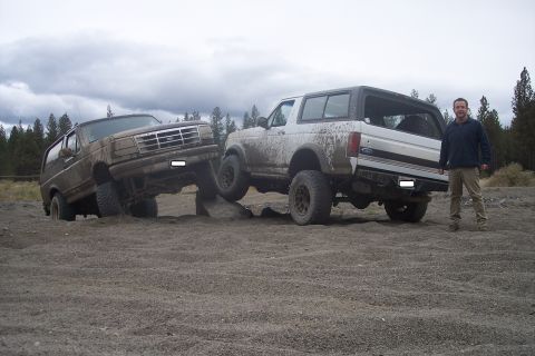 1995 Ford Bronco - Two Ford Broncos navigate a rocky off-road course under a cloudy sky.