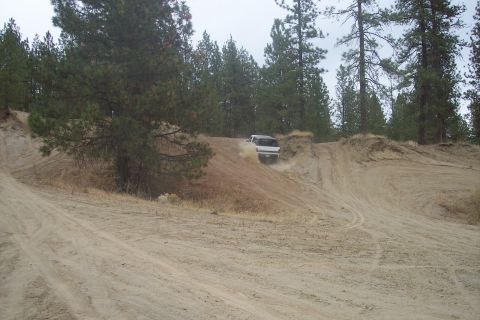 1995 Ford Bronco - SUV navigates a challenging dirt track in a wooded area.