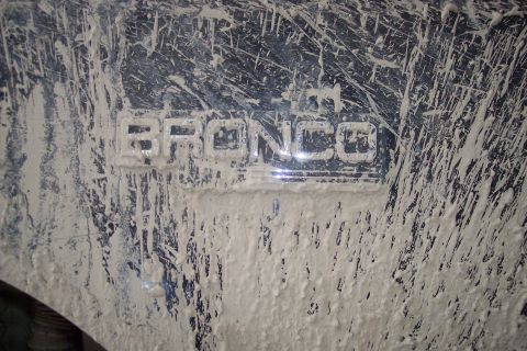 1995 Ford Bronco - The "BRONCO" emblem is clearly visible despite heavy mud coverage on the vehicle's exterior.