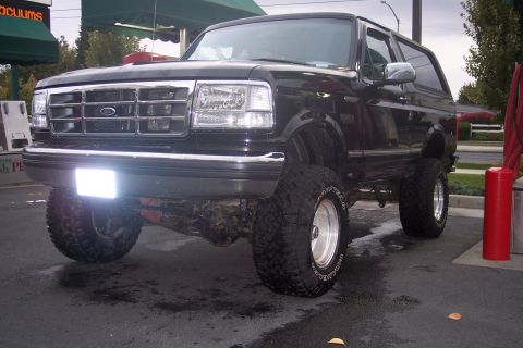 1995 Ford Bronco - This lifted black Ford Bronco features a chrome grille and aggressive off-road tires.