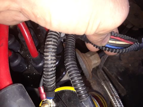 1985 Ford Bronco - Close-up of a vehicle's electrical wiring and ignition components, with a hand manipulating a wire harness.