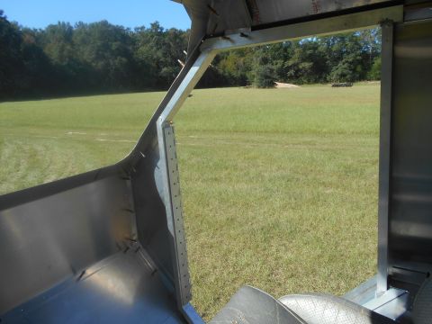 1992 Ford Bronco - The interior of a vehicle shows exposed metal framing and black lining, with a grassy field visible through the open door.