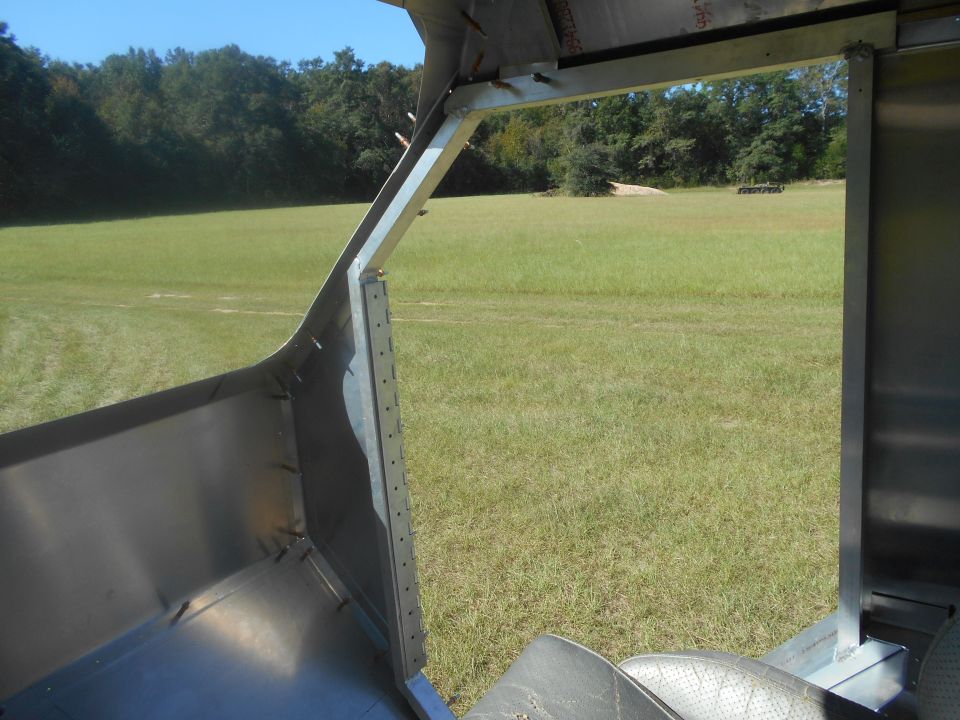 Interior of a vehicle with exposed metal framing and black lining, viewed from the passenger side