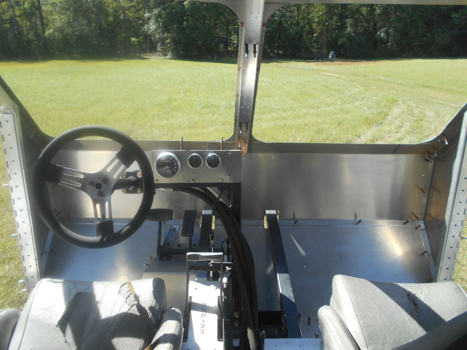 Interior of a custom vehicle with a steering wheel, dashboard gauges, and seats