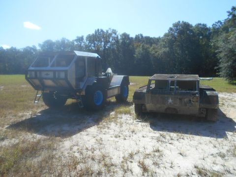 1992 Ford Bronco - Two unique, custom-built vehicles are parked on a sandy, grassy area under a clear blue sky.