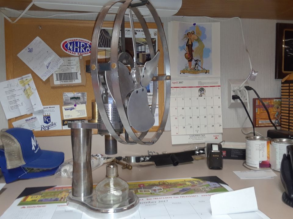 Desk with a metal desk fan, calendar, and various papers