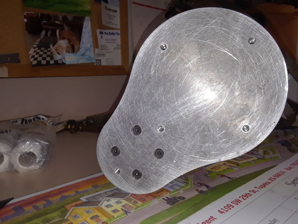 metal disc with screw holes on a table with some papers and tape rolls