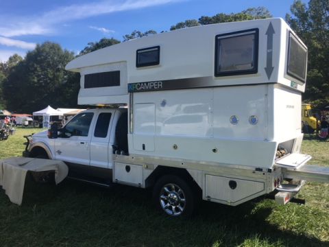 2004 Ford F-150 - A white truck camper with XP CAMPER branding is parked on a grassy field.