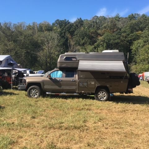 2004 Ford F-150 - A truck camper is parked in a field during the day.