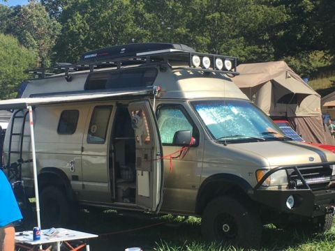 2004 Ford F-150 - A customized van with camping gear is parked outdoors with tents in the background.