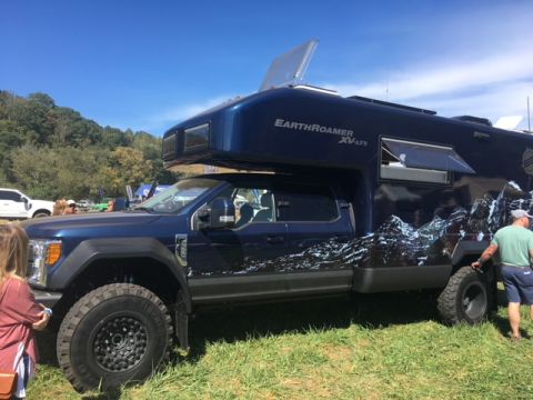 2004 Ford F-150 - A blue Earthroamer XV-LTS camper truck is parked on a grassy field under a clear blue sky.