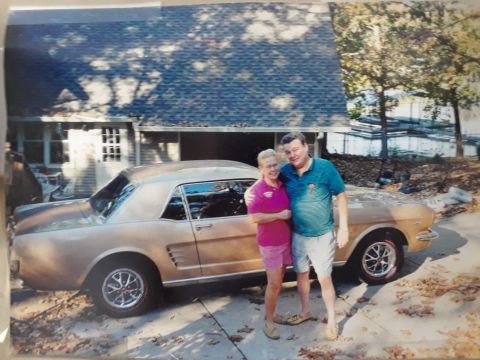 1994 Ford Bronco - A couple stands next to a classic gold Ford Mustang coupe in a driveway.