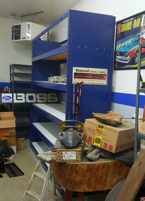 1973 Ford Mustang - A garage interior features storage shelves, automotive signs, and various items on display.