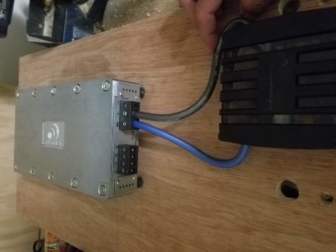 1994 Ford Bronco - A car amplifier is wired to a power supply, mounted on a wooden surface. Text is visible on the amplifier's casing.