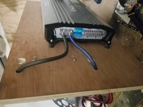 1994 Ford Bronco - A car amplifier is mounted on a wooden surface, with power cables connected to its terminals.