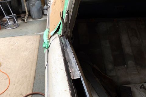 1962 MG B - Close-up of a car's door edge undergoing repair work, with a clamp holding metal in place.