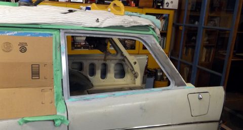 1962 MG B - A car's door is being prepped for repair, with protective tape and primer visible around the window frame.