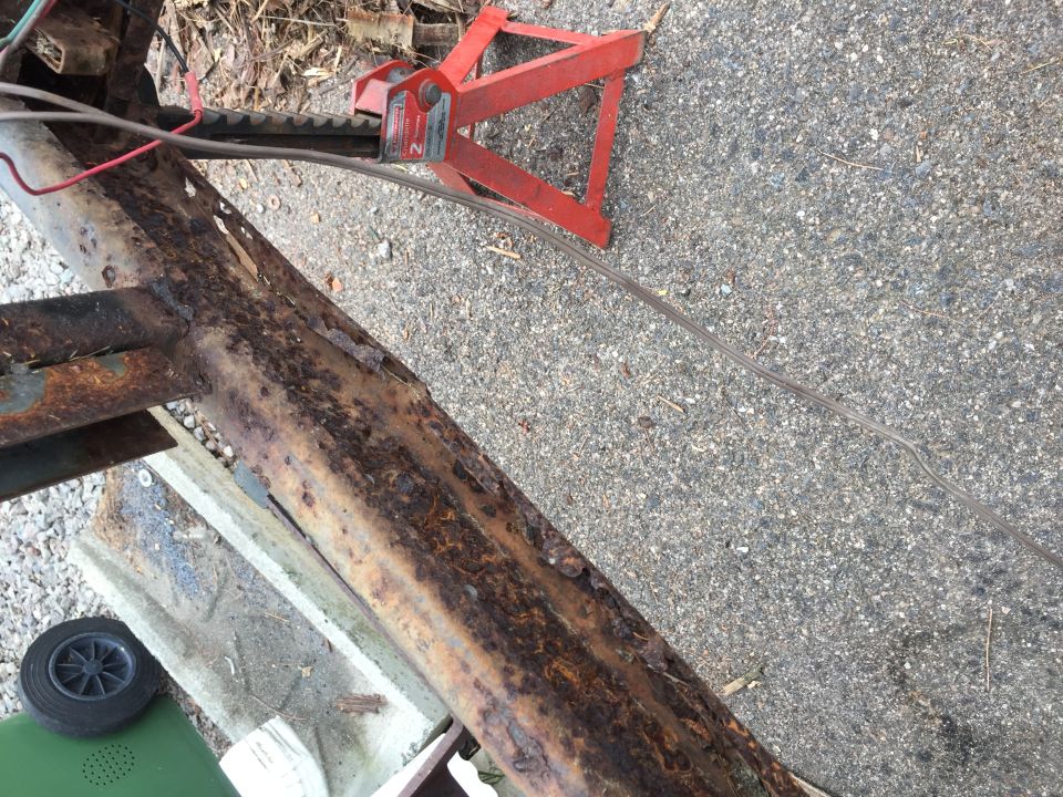 Rusted trailer frame section with red jack stand