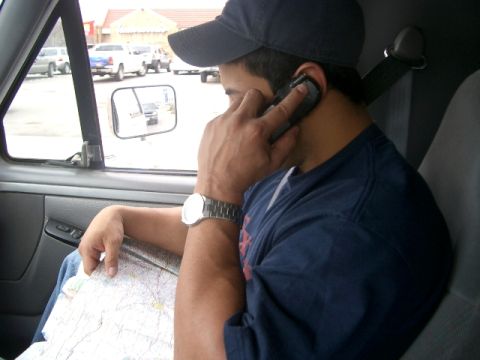 1994 Ford Bronco - Man inside a vehicle, talking on his phone and consulting a map while other vehicles are parked outside.